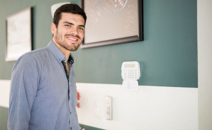 portrait-handsome-young-man-standing-front-keypad-his-home-alarm-system-smiling